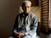 A photo of sitting looking at the camera with light coming in through the blinds to his right