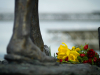 A close-up of a human foot in statue form with flowers laid before it