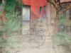 A digitally manipulated photograph of a bicycle parked in front of a set of stairs that lead into a red house. A translucent parchment with ink writing sits as a palimpsest over the image.