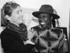 A black and white photograph of a light skinned and dark skinned woman laughing