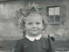 A black and white historical photograph of a young girl smiling at the camera