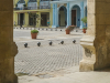 A photograph shot from within a colannade looking out at an empty plaza