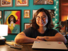 A photograph of bookstore owner Lucy Yu sitting at a desk with book open in front of her