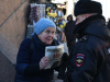 A photograph of an elderly woman holding a pamphlet confronting a police officer