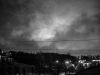 A black and white photograph of a hill, silhouetted against the growing dusk