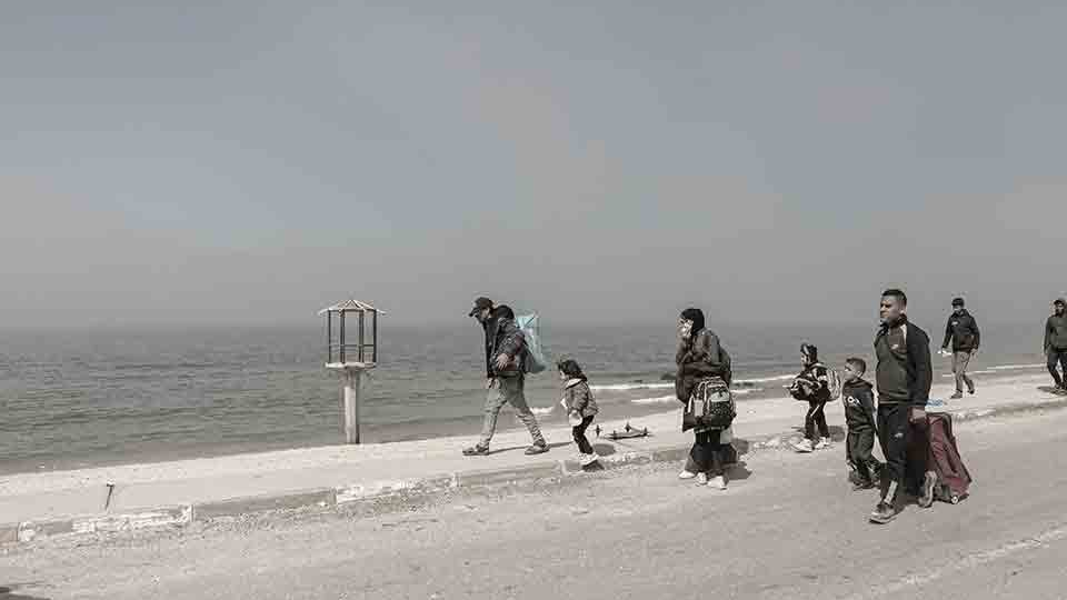 A group of refugees walking along the beach