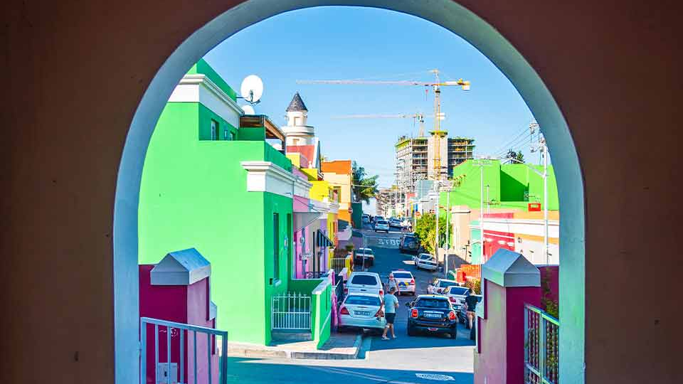 A photograph looking down a colorful city street through a painted archway