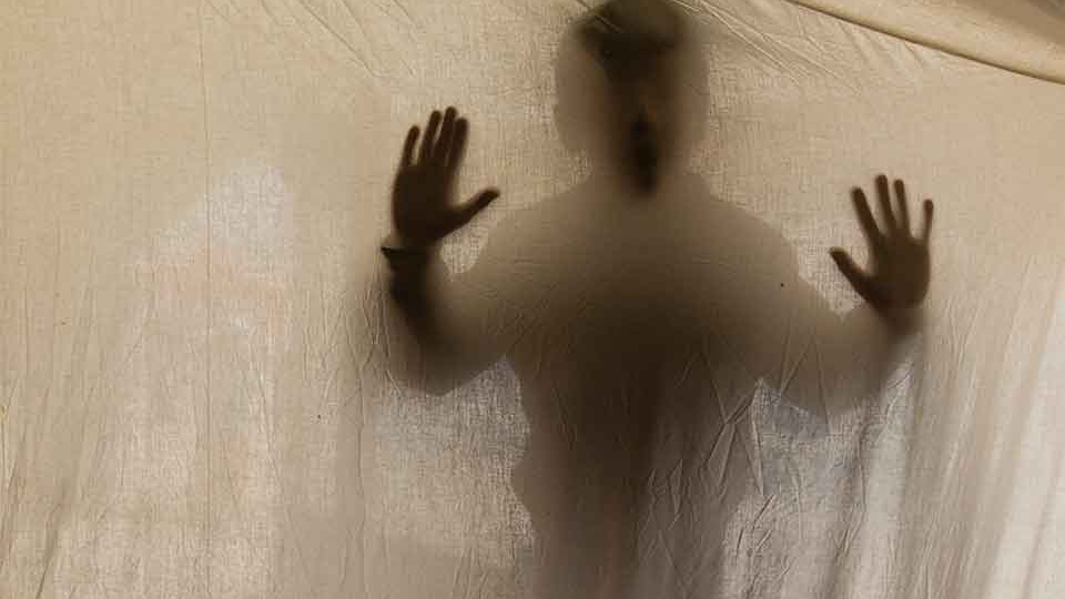 A shadowy figure presses into a translucent cloth