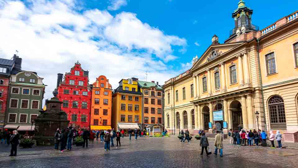 A photograph of a crisp Swedish buildings towering over a stone roadway