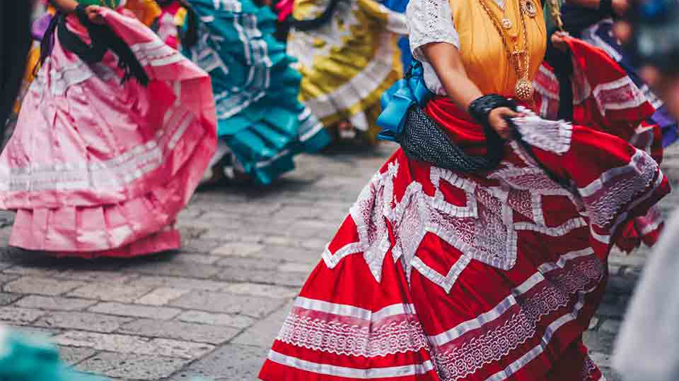 The lower torso of women in traditional Mexican dress dancing in tandem