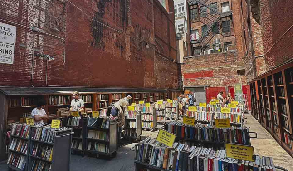 Racks of books on sale outdoors in a city alleyway