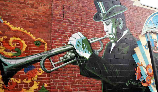 A photograph of a mural featuring a black man in a top hat playing trumpet