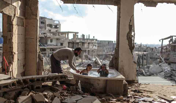 A man bathes two children in the rubble of a bombed-out apartment
