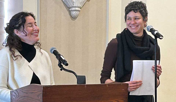 Guadalupe Nettel stands at the lectern laughing while Rosalind Harvey watches her, smiling