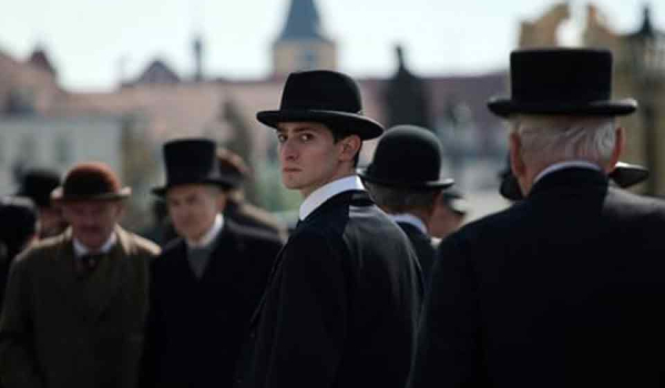 A man in a group of men dressed in suits looks at the viewer