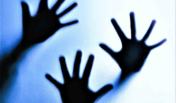 Three hands pressing against glass