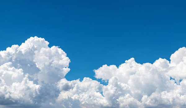 A blue sky filling with puffy clouds from the bottom