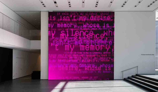Ghostly electronic words inhabit a dark magenta canvas in a white museum hall
