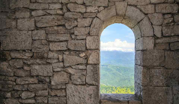 A doorway in a stone wall, looking out on to a field