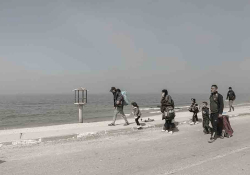 A group of refugees walking along the beach