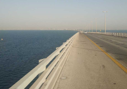 A photograph of a causeway stretching off into the distance beside a body of water