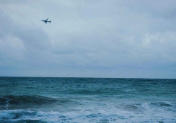 A stormy sea churning beneath a grey-blue, cloud-choked sky