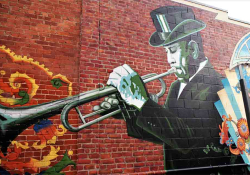 A photograph of a mural featuring a black man in a top hat playing trumpet