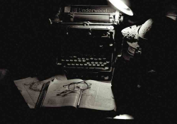 An old manual typewriter harshly lit from above by a desk lamp but otherwise cloaked in shadow. A book lies open in front of it with a pair of reading glasses laying on the open pages