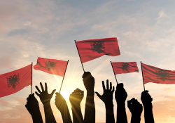 A photograph of hands waving small flags at sunset