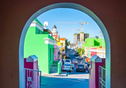 A photograph looking down a colorful city street through a painted archway