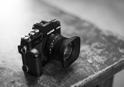 A black and white photo of a Fuji camera on a wooden table