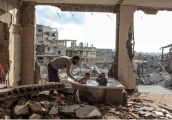 A man bathes two children in the rubble of a bombed-out apartment