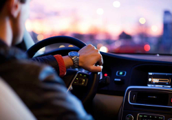 A photograph of a man driving a car shot from over his shoulder