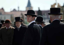 A man in a group of men dressed in suits looks at the viewer