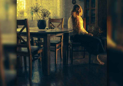 A woman sits in a chair looking at the floor with melancholy