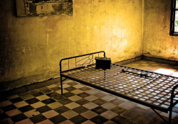A photograph of a cot in a dimly lit prison cell