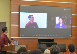 A photograph of Gene Luen Yang talking to Kelvin Yu via Zoom in front of a festival audience