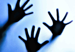 Three hands pressing against glass
