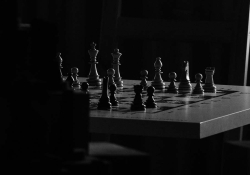 A chessboard in a room consumed by shadows