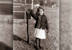 A black and white photograph of a young girl waving at the camera