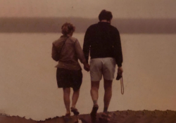 An aged photograph of a couple walking along a beach