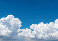 A blue sky filling with puffy clouds from the bottom