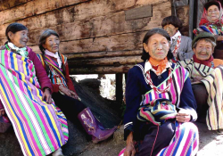 A small clutch of elderly women with face tattoos, garbed in native dress