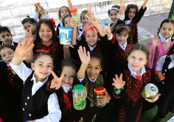 A photograph of a group of Palestinian children in school uniforms smiling for the camera which is above them