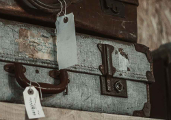 a close-up of a stack of old battered suitcase with white tags attached to them