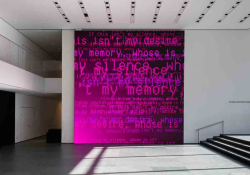 Ghostly electronic words inhabit a dark magenta canvas in a white museum hall