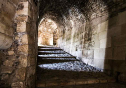 A photograph taken from inside a covered stone hallway