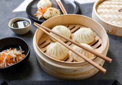 A photograph of steamed dumplings in a bamboo tray