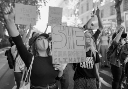 A black and white photograph of young people, many wearing masks, protesting climate inaction