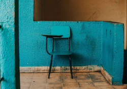 A children's school desk painted blue, sitting in front of a wall painted similarly blue